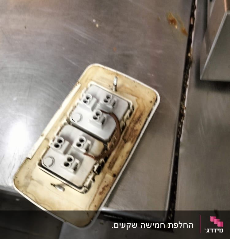 Electrical outlet with exposed wiring on metal surface